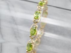 A lovely citrus combination, bright lime green peridot reflects prettily in the yellow gold of this bracelet! Each stone is held in place by four secure prongs and framed with scrolling accents. This is a versatile bracelet that can be either dressed up or down depending on the occasion. Metal: 10K Yellow Gold Gem: 12 Peridots Gem Measurements: 5 x 7 mm, Oval Width: 7 mm Length: 6.75 Inches Marks: "10K" Stamped on the clasp Gold Tennis Bracelet, Bracelet Layering, Cameo Ring, August Birthstone, Diamond Chain, Green Diamond, Green Peridot, Layered Bracelets, August Birth Stone