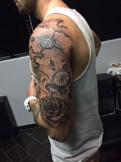 a man with a compass and rose tattoo on his arm is standing in front of a mirror