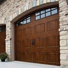 a brown garage door with two windows in front of a brick wall and stone pillars