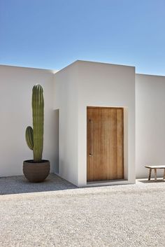 a house with a cactus in front of it and a bench next to the door