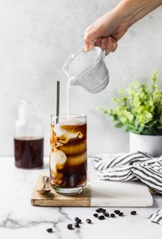 someone pouring coffee into a glass with ice