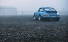 a blue car parked on top of a gravel field