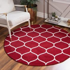 a red rug with white circles on it in a living room next to a chair and potted plant