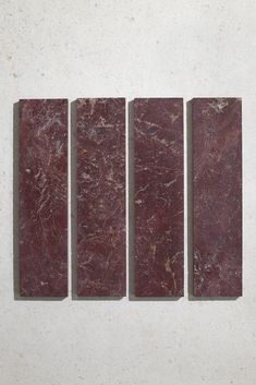 four pieces of red marble sitting on top of a white wall