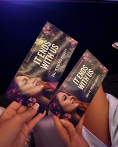 two book covers being held up in front of a woman's face and hands