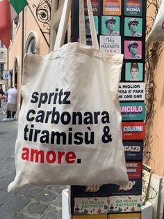 a white bag hanging from the side of a building with words on it that read, spritz carbonara tiamisu & amore