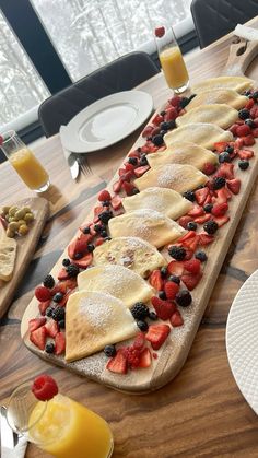 a wooden table topped with pancakes covered in fruit