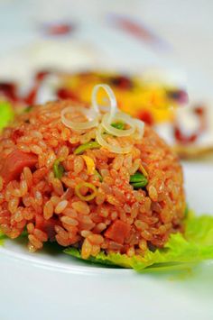 a white plate topped with red rice and lettuce