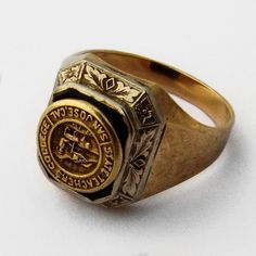 "Vintage 10 K (.417) yellow gold signet ring, having chamfered rectangle form front, decorated with applied white gold band in foliate pattern and Onyx stone inlay. Atop the stone, there is an attached yellow gold medallion, featuring embossed depiction of the Great Seal of the State of California and inscription \"San Jose, Cal. State Teachers College\". This important ring is a size 6 1/4 and weighs 4.8 grams. Eb8894" Rectangular 14k Stamped Signet Ring Collectible, Art Deco Yellow Gold Enamel Ring For Formal Occasions, Formal Yellow Gold Art Deco Enamel Ring, Art Deco Formal Yellow Gold Enamel Ring, Formal Art Deco Yellow Gold Enamel Ring, Formal Rectangular Signet Ring With Polished Finish, Modernist Rectangular Signet Ring For Anniversary, Modernist Rectangular Signet Ring With Polished Finish, Rectangular Modernist Signet Ring With Polished Finish