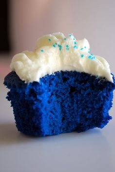 a blue velvet cupcake with white frosting and sprinkles on it