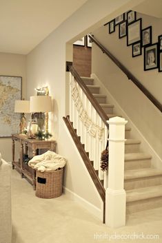 a living room filled with furniture and pictures on the wall next to a stair case