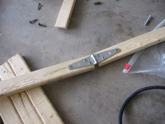 a pair of wooden clamps sitting on top of a floor next to a piece of wood