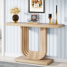 a wooden table with a book and vase on it in front of a blue striped wall