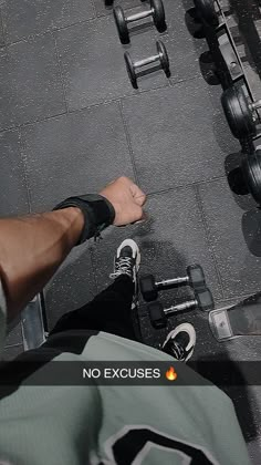 a man is sitting on the ground with his feet up in front of dumbbells