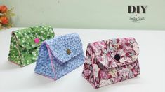 three small purses sitting next to each other on a white counter top with flowers in the background