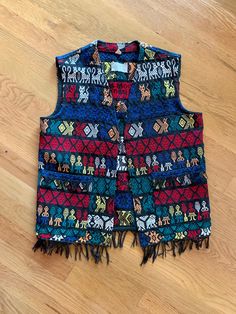 This vest was handwoven in Guatemala, and has pockets and fringe. This is a very colorful vest with figures, animals and designs and it is in excellent condition. It measures: 37 inches around the bust, but isn't meant to close. 23 inches from shoulder to the bottom. Dollhouse Shoes, Colorful Vest, Fringe Vest, Tiny Dolls, Neck Piece, Embroidered Bag, Vest Outfits, Beaded Fringe, Guatemala