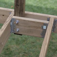 a wooden structure with metal brackets on the side and grass in the backround