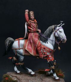 a figurine of a man riding on the back of a white and black horse