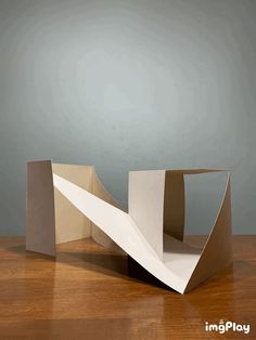 an origami sculpture sitting on top of a wooden table next to a gray wall