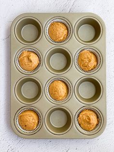 a muffin tin filled with cupcakes sitting on top of a white wall