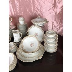 a table topped with lots of white and gold china dishes, cups and saucers