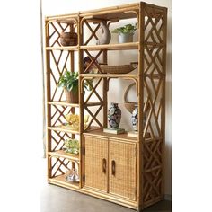 a bamboo shelf with baskets and vases on the top, next to a wall