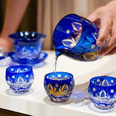 a person pouring water into blue glass bowls