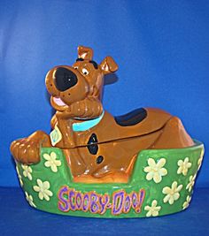 a toy dog sitting on top of a flowered pot with the words scooby doo