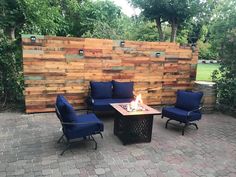 a fire pit sitting in the middle of a patio surrounded by wooden pallet walls