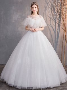 a woman in a white wedding dress standing next to a tree