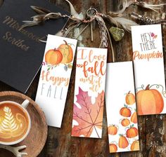 some cards that are sitting on a table with a cup of coffee and two pumpkins