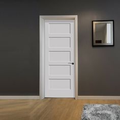 an empty room with a white door and mirror on the wall next to a rug