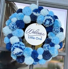 a blue and white wreath with the words welcome little one on it