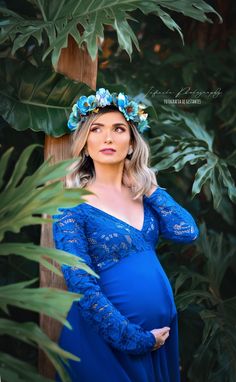 a pregnant woman wearing a blue dress and flower crown