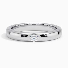 a white gold wedding ring with a round diamond in the center, on a plain surface