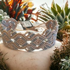 a close up of a bracelet on a rock with succulents in the background