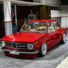 an old red car parked in front of a garage