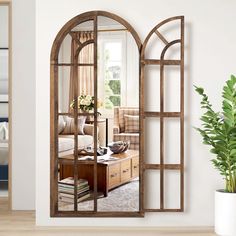 a living room with an arched window and wooden furniture on the floor next to a potted plant