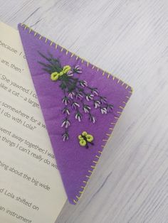 a bookmark with flowers on it sitting next to an open book