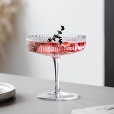 a pink drink in a wine glass on a table