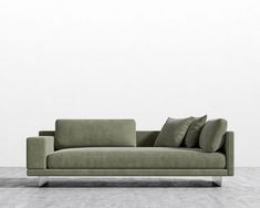 a green couch sitting on top of a wooden floor next to a white wall in an empty room