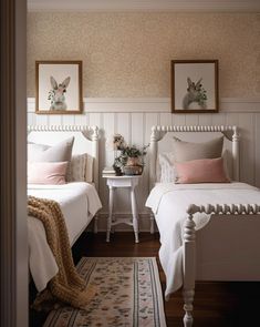 two white beds in a bedroom with pink and white decor on the headboard, nightstands and rug