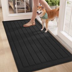 a woman is standing on the door mat with her dog