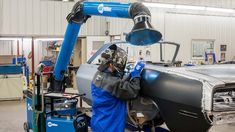 a car being worked on in a factory with an engineer working on the front end