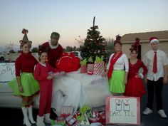 group of people dressed up in costumes standing next to a car with presents on it