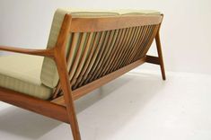 a wooden bench sitting on top of a white floor next to a chair with green cushions