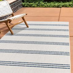 a white and blue striped rug sitting on top of a patio floor next to a wooden bench