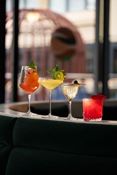 three different types of cocktails sitting on a table in front of a large window