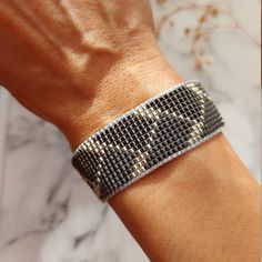 a woman's arm wearing a bracelet with silver and black beading on it