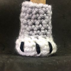 a close up of a crocheted slipper on a black surface with a wooden stick